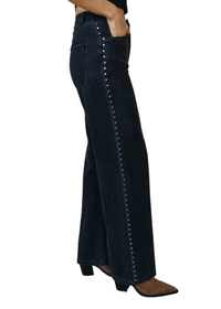 Dark blue flared jeans with decorative studs on a neutral background